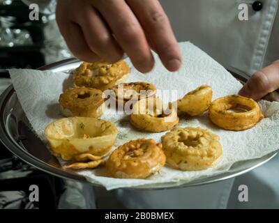 Gros morceaux d'oignons frits disposés sur une serviette de cuisine en papier à sécher avant de manger. Banque D'Images