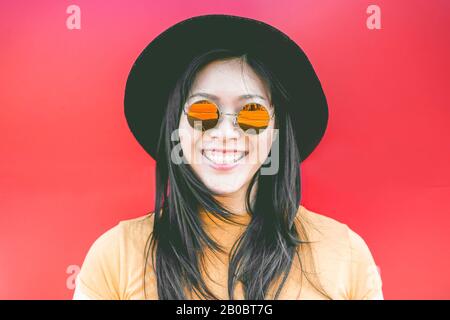 Portrait d'une heureuse fille asiatique souriant avec des lunettes de soleil vintage - jeune femme chinoise qui s'amuse se posant devant l'appareil photo - mode, tendance et moulin Banque D'Images