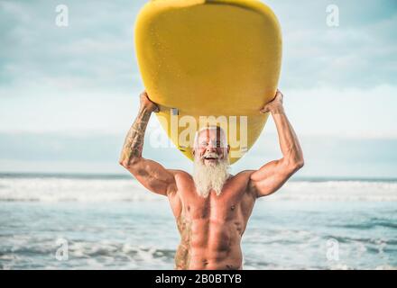 Homme à la mode senior qui fait du surf avec le longboard - Un Vieil homme Heureux qui s'amuse à faire du sport extrême - un concept De Personnes âgées Joyeuses - se concentrer sur son visage Banque D'Images