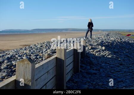 Femme A Pris une photo sur une crête de galet au-dessus de la plage à Westward Ho! Sur le sentier côtier sud-ouest, North Devon, Angleterre, Royaume-Uni. Banque D'Images