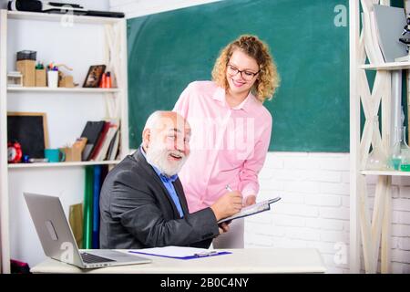 Vérifier les devoirs. Éducateur et étudiant regardant le livre. Expliquer un sujet difficile. L'étudiant est perplexe par quelques informations. Un étudiant demande à l'enseignant la tâche. Résolution des tâches mathématiques. Concept d'éducation scolaire. Banque D'Images