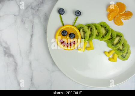 drôle de ver de fruits sur la plaque blanche dessert sain pour les enfants . Banque D'Images