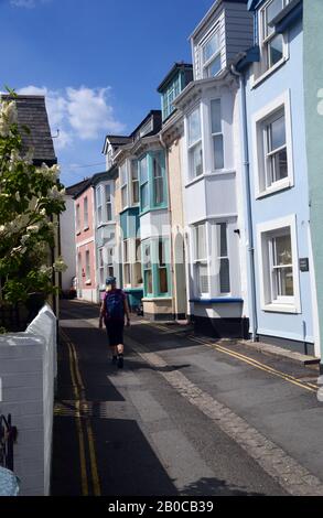 Femme Hiker marchant sur la rue Irsha une rue étroite de maisons mitoyennes De Couleur Pastel à Appledore sur le sentier de la côte sud-ouest. Devon Nord. Banque D'Images