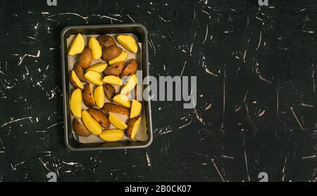 Les pommes de terre en tranches se trouvent dans un plat de cuisson au four. Cuisine pour le déjeuner, le dîner ou un festin festif. Couche plate, espace de copie Banque D'Images