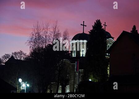 Église orthodoxe de Serbie avec deux croix et dômes éclairés par le soleil levant à l'aube. Banque D'Images