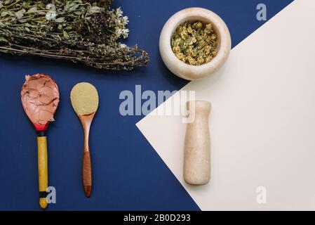 Mélanger les fleurs séchées dans un mortier de marbre pour créer des cosmétiques et gommage pour nettoyer le visage. Argile jaune pour améliorer l'état de la peau dans une cuillère en bois. Bo Banque D'Images