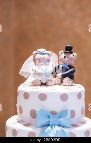 Un topper de gâteau de mariage sur un gâteau de mariage à deux niveaux à pois. Les toppers sont de jolis ours habillés comme une mariée et un marié Banque D'Images