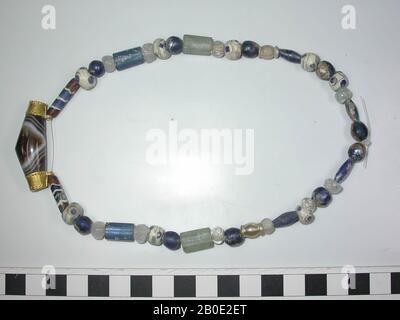 Collier de perles rondes à aplaties elliptiques rondes, sphériques, cylindriques, polygonales et de forme différente de verre, dans un cas avec un cadre doré. Presque complètement symétrique dans la construction. 10 perles rondes de verre bleu, 4 perles elliptiques de verre blanc incolore à laiteux, 1 perle supplémentaire de verre ditto, 10 perles rondes de verre blanc opaque aux yeux bleus et bandes et bordures grises à noires, 2 perles de verre incolore à bobine, 2 perles polygonales de verre bleu, 2 perles cylindriques de verre onyx brun, blanc et bleu, et enfin une perle allongée de pierre flammée brun-blanc entre Banque D'Images