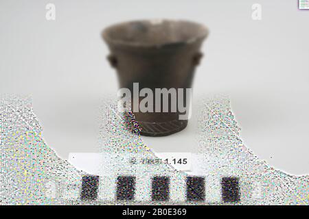 Une tasse avec une bordure extérieure. La tasse est en faïence brun-gris et a une décoration primitive sculptée sur le mur extérieur, remplie à l'origine de pâte blanche, vaisselle, faïence, H 7,5 cm, D 7,6 cm, fer Age I 1100-1000 BC. , Iran Banque D'Images