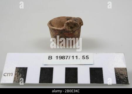 Un bol miniature en faïence à fond plat. Le mur monte en flèche et se renge légèrement. L'arête est courbée vers l'extérieur et non épaissir. Sur le bord il y a une petite tête d'animal modélisée avec un klaxon arrondi vers le bas de chaque côté. Les oreilles sont indiquées par un trou rond. L'extérieur a un revêtement beige-vert avec une peinture marron foncé. Une ligne horizontale double est placée sous le bord et trois lignes zigzag horizontales sur le ventre. Sur le dessus et les cornes de la tête d'animal nous voyons des rayures croisées. L'intérieur a un revêtement beige, vaisselle, faïence, fait main, H 3,3 cm, D 3,3 cm, Bronze Age 1800-1150 Banque D'Images