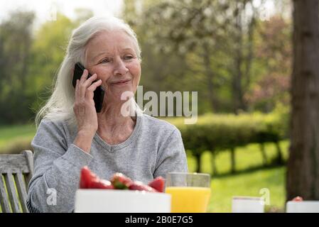 Femme senior souriante parlant sur smartphone Banque D'Images