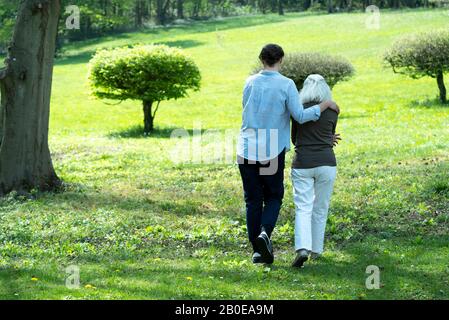 Soignant et femme senior marchant dans le jardin Banque D'Images