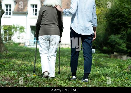 Soignant et femme senior marchant dans le jardin Banque D'Images