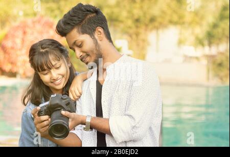 Joli Couple regardant des photos sur l'écran de l'appareil photo - Heureux jeune photographe professionnel montrant des images à modéliser sur son reflex numérique - concept de modèle et Banque D'Images