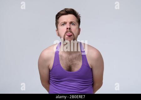 Homme sportif avec moustache drôle qui s'encolle sa langue, taquinant quelqu'un. Banque D'Images