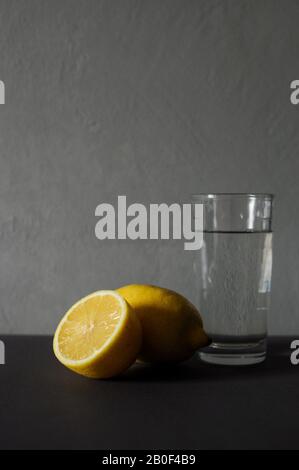 Verre d'eau pure avec une tranche de citron sur fond gris. Detox du matin. Banque D'Images