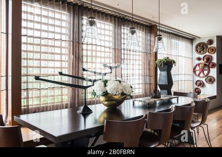 Luminaires suspendus en verre au-dessus de la table à manger De L'Arxe avec hydracea dans un vase en cuivre Banque D'Images