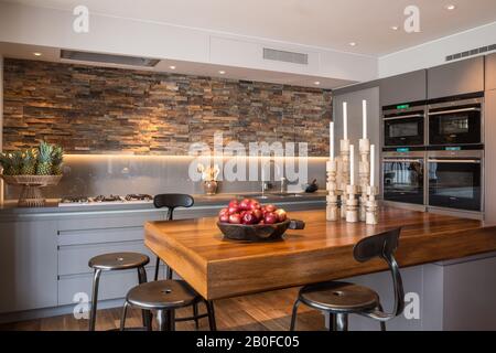 Bar à petit-déjeuner en teck avec murs ornés d'ardoise dans la cuisine de l'appartement moderne de West London. Banque D'Images