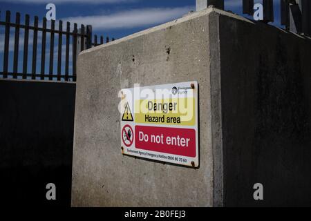 Danger signe de zone dangereuse de l'agence environnementale sur les tuyaux de sortie d'eau menant à la mer à Lepe Beach Hampshire. Banque D'Images