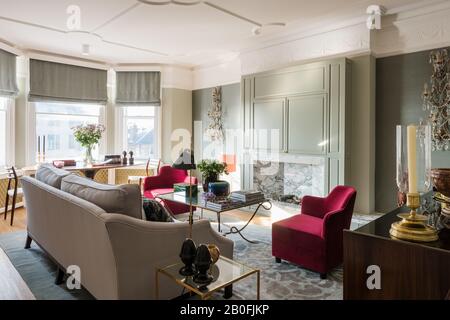 Mélange de pièces anciennes et contemporaines dans le style victorien redessiné avec des fauteuils sur mesure en velours rouge