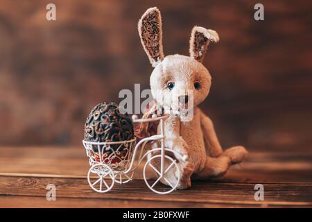 Oeuf vintage dans bice de Pâques, lapin assis près de la bicyclette Banque D'Images