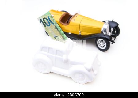 La caisse en céramique en forme de voiture avec un billet à l'intérieur avec une voiture modèle derrière. Il peut être le symbole des coûts des réparations, des investissements et des économies de la voiture Banque D'Images