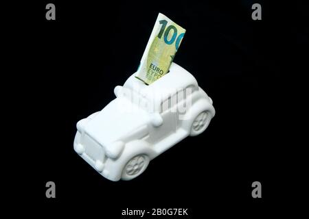 La boîte en céramique en forme de voiture avec un billet à l'intérieur. Elle peut être le symbole des coûts des réparations, des investissements, des économies ou de l'assurance de la voiture. Banque D'Images