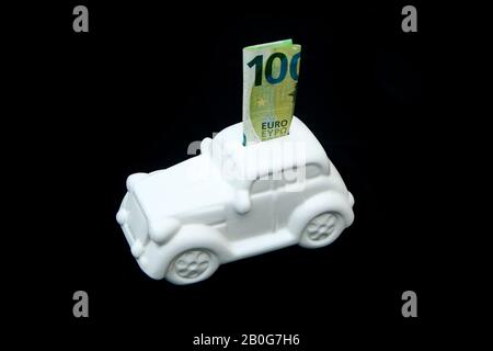 La boîte en céramique en forme de voiture avec un billet à l'intérieur. Elle peut être le symbole des coûts des réparations, des investissements, des économies ou de l'assurance de la voiture. Banque D'Images