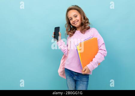 Une jeune fille d'école joyeuse avec des livres en blouse violette sourires Banque D'Images