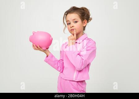 portrait d'une fille de pensée dans un costume rose tenant un pot d'argent sur un fond blanc avec espace de copie Banque D'Images