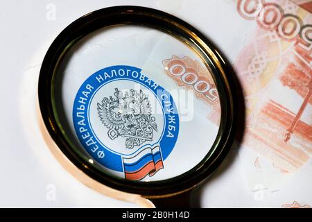 Emblème du service fiscal fédéral de la Fédération de Russie sous une loupe sur le fond de 5000 roubles factures Banque D'Images