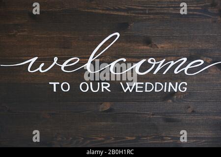 Planche en bois avec l'inscription Bienvenue à notre mariage. Lettrage blanc sur une surface en bois sombre - bienvenue à notre mariage. Inscription de salutation sur un Banque D'Images