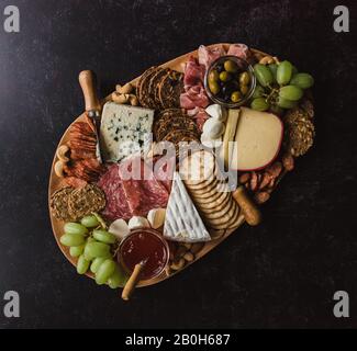 Vue de dessus du plateau de charcuterie avec viandes et fromages sur une surface noire. Banque D'Images