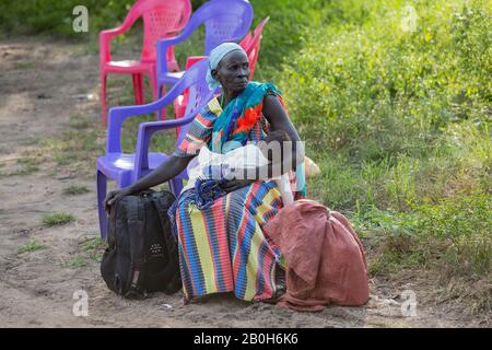 30.10.2019, Opanya, Gambela, Ethiopie - une femme plus âgée est assise sur une chaise en plastique avec un petit enfant dans ses bras et attend un tour. Documentation du projet Banque D'Images