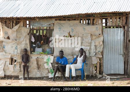 31.10.2019, Belinkum, Gambela, Ethiopie - devant une boutique de village faite de fer et de bois ondulés, les jeunes hommes s'assoient sur une chaise en plastique et sto en bois Banque D'Images