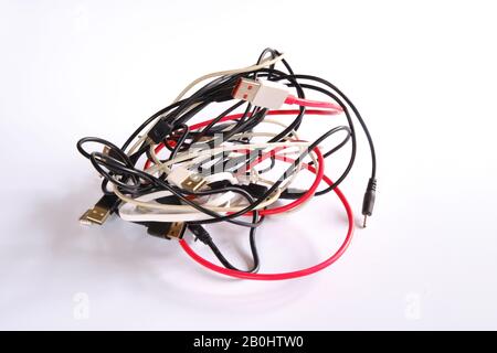 Un ensemble de câbles de charge assortis dans un désordre de balle emmêlé sur un fond blanc Banque D'Images