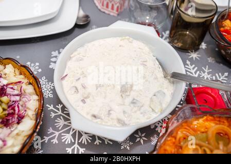 Les harengs crus dans la crème aigre, se tenant dans un bol sur la table de Noël en Pologne. Banque D'Images