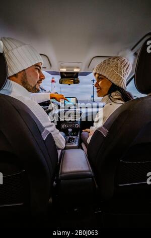 Vue arrière des jeunes couples en utilisant une carte sur un voyage pour les directions. Jeune homme et femme lisant une carte en étant assis dans une voiture. Banque D'Images