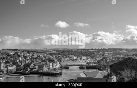 Port de Whitby et ville donnant vers l'intérieur. Les bâtiments de la ville se regroupent autour du port et un pont s'étend sur l'eau. Un ciel nuageux est au-dessus. Banque D'Images