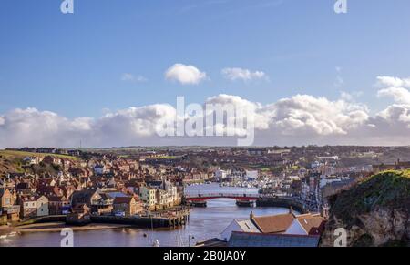 Port de Whitby et ville donnant vers l'intérieur. Les bâtiments de la ville se regroupent autour du port et un pont s'étend sur l'eau. Un ciel nuageux est au-dessus. Banque D'Images