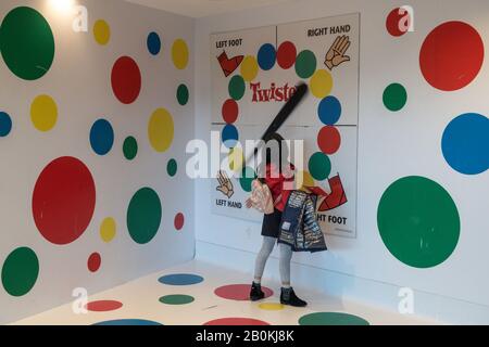 Jeune fille Jouant dans La configuration de jeu de Twister géant dans le Hall de l'hôtel TWA , JFK, NYC, USA Banque D'Images