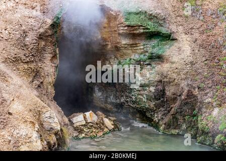 Entrée de la grotte avec vapeur et gaz sortant. Source chaude à l'entrée de la grotte. Banque D'Images