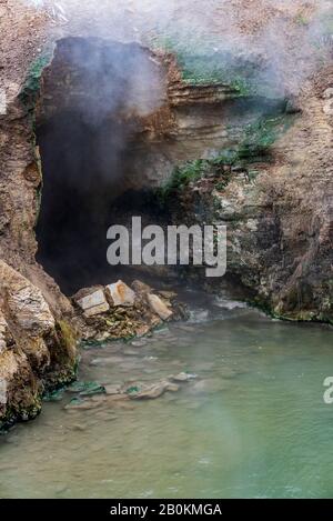 Entrée de la grotte avec vapeur et gaz sortant. Source chaude à l'entrée de la grotte. Banque D'Images