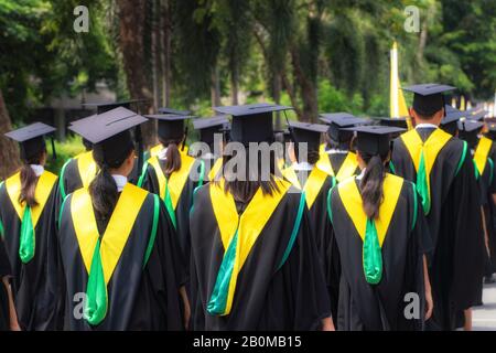 Vue arrière du groupe de diplômés universitaires en robes noires s'aligne pour le diplôme à l'université cérémonie de remise de diplômes. L'éducation Concept félicitations, stu Banque D'Images