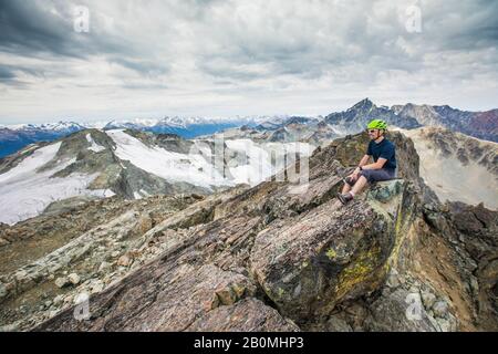 Le grimpeur est assis sur le sommet rocheux d'une montagne. Banque D'Images