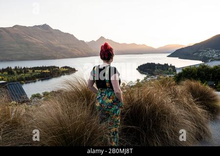 Femme surplombant Queenstown et le lac, au coucher du soleil en Nouvelle-Zélande Banque D'Images