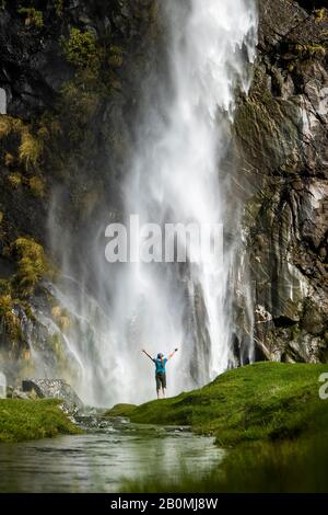 Figure debout devant un jet en cascade, dans un paysage de nature verte Banque D'Images