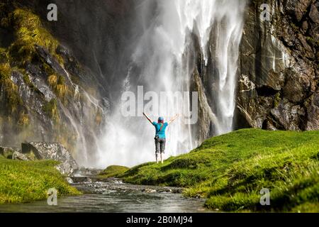 Figure debout devant un jet en cascade, dans un paysage de nature verte Banque D'Images