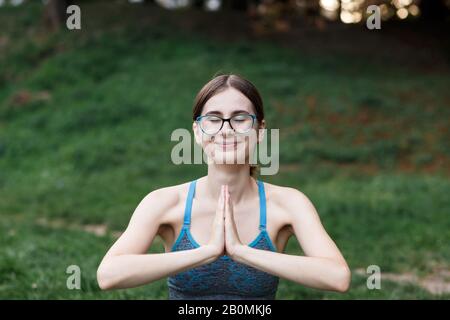 La fille détendue fait du yoga dans le parc sur la moquette Banque D'Images