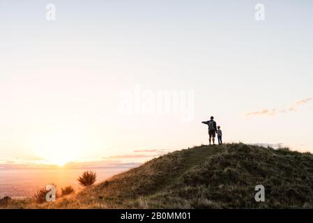 Papa et enfant regardant un beau coucher de soleil en Nouvelle-Zélande Banque D'Images